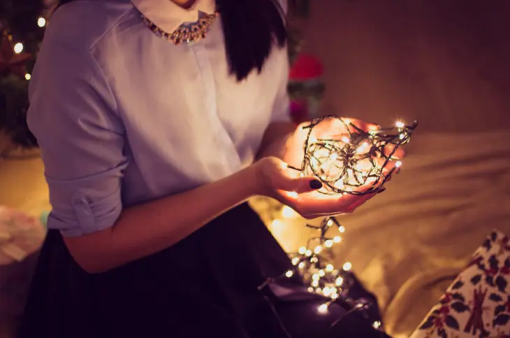Woman holding a string of lights in her hands.