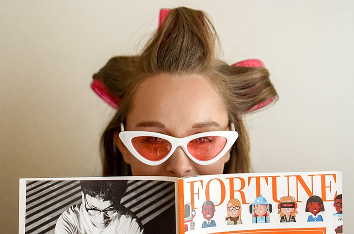 Woman wearing curlers and holding a magazine.
