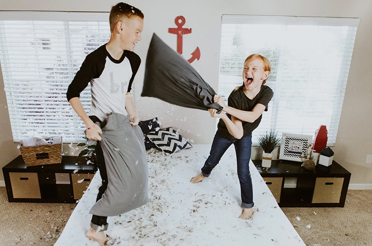 Two kids having pillow fight at home.