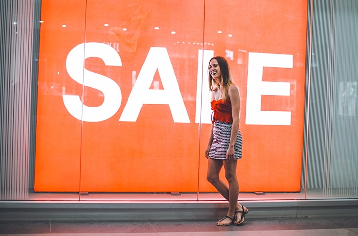 woman in front of a store with sales