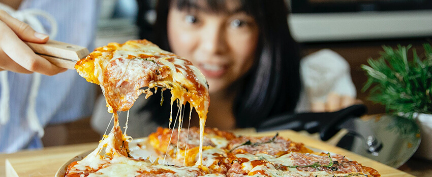 woman looking at a slice of pizza