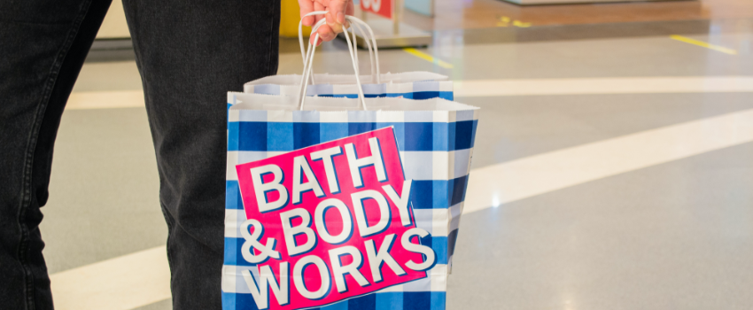 a female customer holds paper bags branded bath and body works